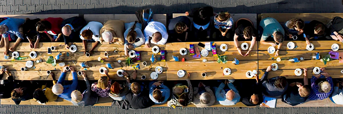 Lange Kaffeetafel mit Menschen auf Bierbänken